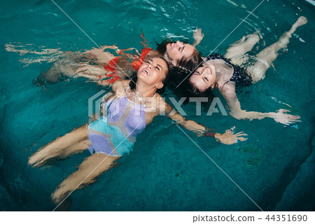 Funny female teenagers fooling around in the swimming pool laughing and enjoying their weekends Funny female teenagers fooling around in the swimming pool laughing and enjoying their weekends 44351690