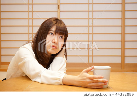 Young Japanese woman relaxing in Japanese room with tatami and shoji Young Japanese woman relaxing in Japanese room with tatami and shoji 44352099