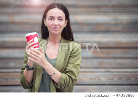 Woman drinking tasty coffee outdoors in the park Woman drinking tasty coffee outdoors in the park 44358686