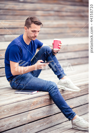 Man is reading text message on mobile phone while walking in the park Man is reading text message on mobile phone while walking in the park 44358710
