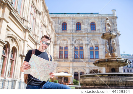 Man tourist with a city map and backpack in Europe street. Caucasian boy looking with map of Man tourist with a city map and backpack in Europe street. Caucasian boy looking with map of 44359364
