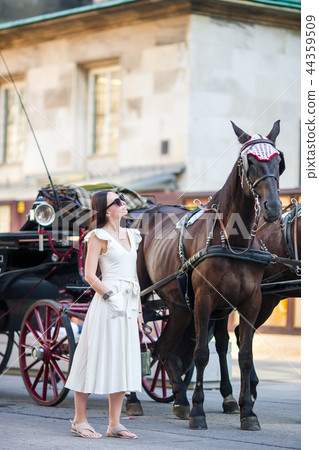 Tourist girl enjoying a stroll through Vienna and looking at the beautiful horses in the carriage 44359509