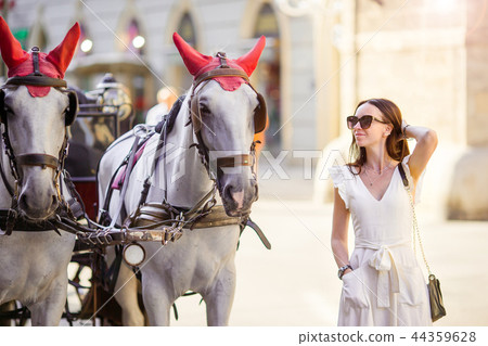 Tourist girl enjoying a stroll through Vienna and looking at the beautiful horses in the carriage 44359628