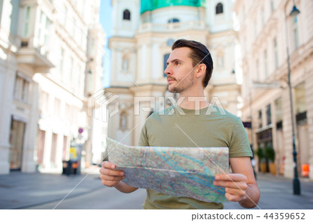 Man tourist with a city map and backpack in Europe street. Caucasian boy looking with map of 44359652
