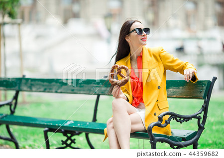 Beautiful young woman holding pretzel and relaxing in park 44359682