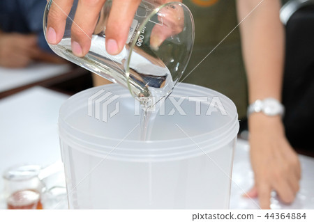 hand pouring chemical ingredient for making shampoo 44364884