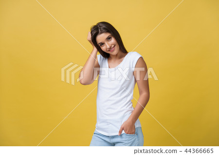 Smiling beautiful young woman in white shirt looking to camera. Three quarter length studio shot on 44366665