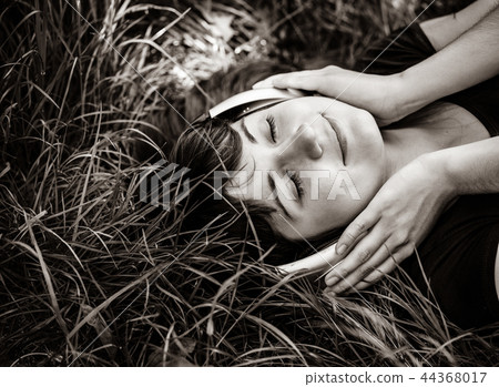 Brunette girl lying at grass with headphones in summer time Brunette girl lying at grass with headphones in summer time 44368017