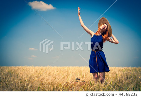 Redhead girl at spring wheat field. 44368232
