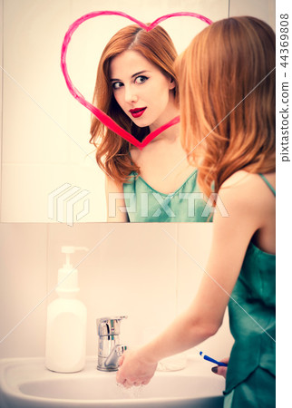 girl near mirror with heart it in bathroom. girl near mirror with heart it in bathroom. 44369808