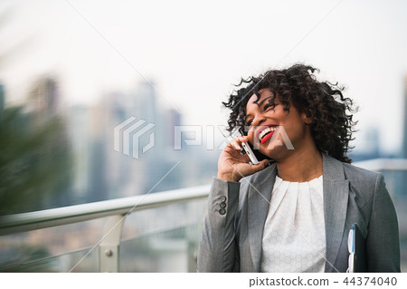 A portrait of a businesswoman standing on a terrace, making a phone call. 44374040