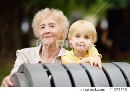 Beautiful granny and her little grandchild together in park Beautiful granny and her little grandchild together in park 44374759