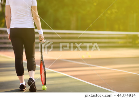 Young female tennis player with tennis ball and racket preparing to serve 44374914