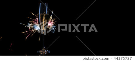 A tall glass with champagne in the light of Bengal lights A tall glass with champagne in the light of Bengal lights 44375727