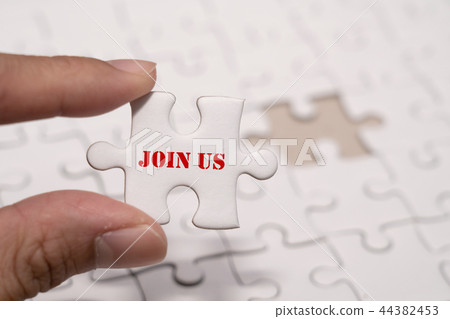 Hand holding a piece of join us wording jigsaw Hand holding a piece of join us wording jigsaw 44382453