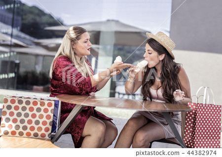 Positive happy women eating tasty ice cream Positive happy women eating tasty ice cream 44382974