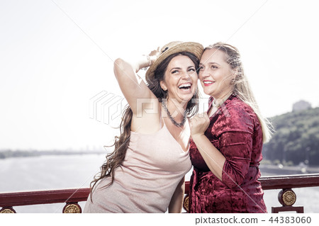 Joyful delighted brunette woman holding her hat Joyful delighted brunette woman holding her hat 44383060