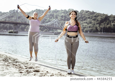 Delighted positive women jumping on the beach 44384255