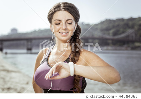 Delighted positive nice woman checking the time Delighted positive nice woman checking the time 44384363