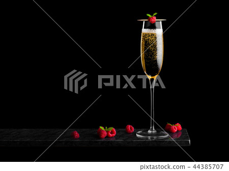Elegant glass of yellow champagne with raspberry 44385707