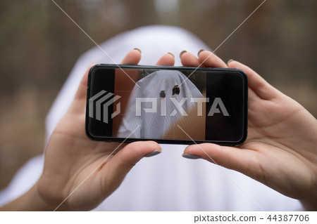 Woman in halloween ghost costume make selfie in the forest. Woman in halloween ghost costume make selfie in the forest. 44387706