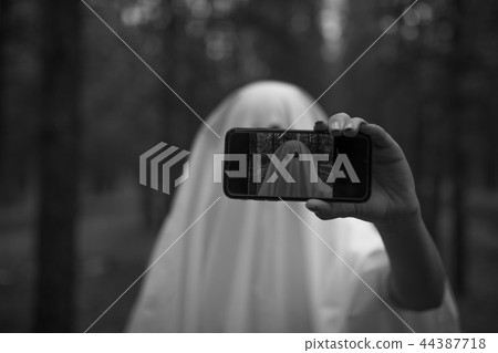 Woman in halloween ghost costume make selfie in the forest. Woman in halloween ghost costume make selfie in the forest. 44387718
