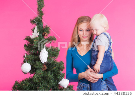 Christmas and holiday concept - Portrait of smiling woman holding her little daughter near Christmas Christmas and holiday concept - Portrait of smiling woman holding her little daughter near Christmas 44388136