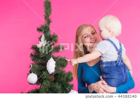 Holidays, family and christmas concept - young mom with her little daughter near christmas tree on Holidays, family and christmas concept - young mom with her little daughter near christmas tree on 44388140