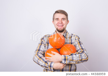 Smiling man holding pumpkins over white background Smiling man holding pumpkins over white background 44388959