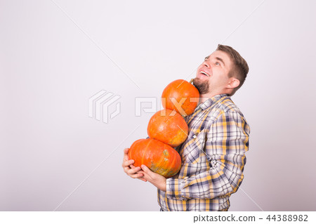 Autumn, harvest and agriculture concept - Smiling man holding pumpkins over white background with Autumn, harvest and agriculture concept - Smiling man holding pumpkins over white background with 44388982