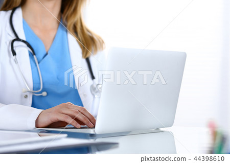 Doctor typing on laptop computer while sitting at the glass desk in hospital office. Physician at Doctor typing on laptop computer while sitting at the glass desk in hospital office. Physician at 44398610