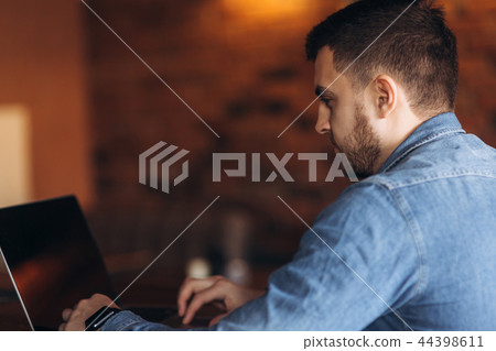 Young programmer working on a laptop in a cafe Young programmer working on a laptop in a cafe 44398611
