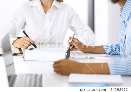 Two female accountants checking financial statement or counting by calculator income for tax form Two female accountants checking financial statement or counting by calculator income for tax form 44398612