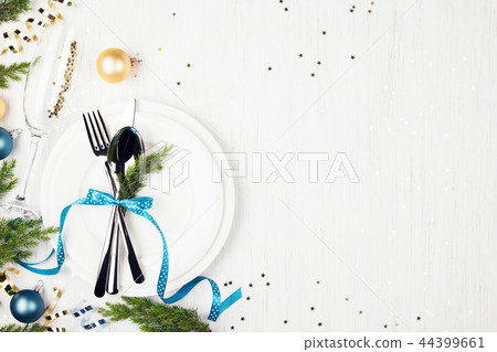 Christmas table setting with blue and golden decorations and evergreens. Christmas table setting with blue and golden decorations and evergreens. 44399661