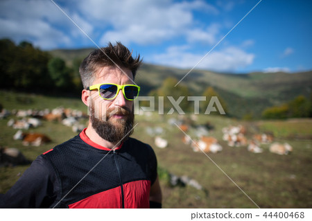Sporty man with beard near a cows pasture Sporty man with beard near a cows pasture 44400468