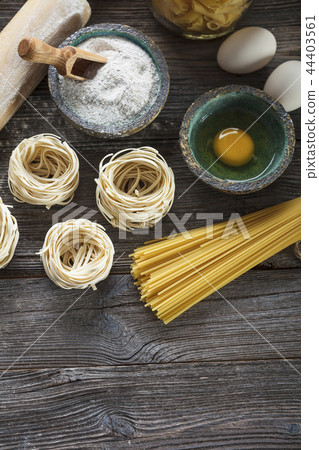 A set of raw pasta and addons on wooden table 44403561
