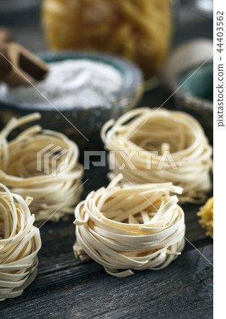 A set of raw pasta and addons on wooden table 44403562