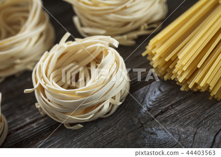 A set of raw pasta and addons on wooden table 44403563
