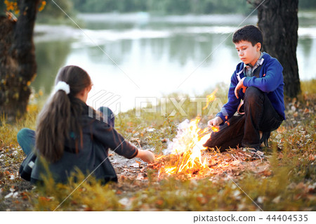 boy and girl sitting on river Bank, make a fire 44404535