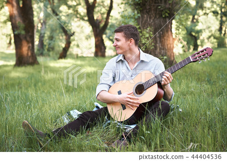 young man playing guitar in the forest young man playing guitar in the forest 44404536