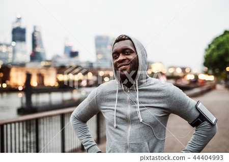 Black man runner with smartphone in an armband on the bridge in a city, resting. Black man runner with smartphone in an armband on the bridge in a city, resting. 44404993