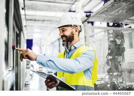 A portrait of an industrial man engineer with clipboard in a factory, working. 44405087