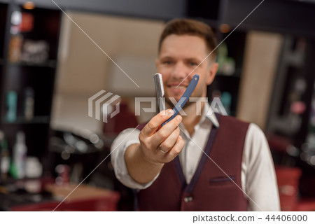 Male hairdresser looking at camera and holding instrument for hair. Male hairdresser looking at camera and holding instrument for hair. 44406000