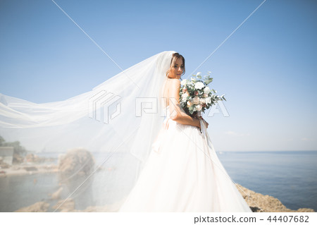 Lovely bride in white wedding dress posing near the sea with beautiful background Lovely bride in white wedding dress posing near the sea with beautiful background 44407682