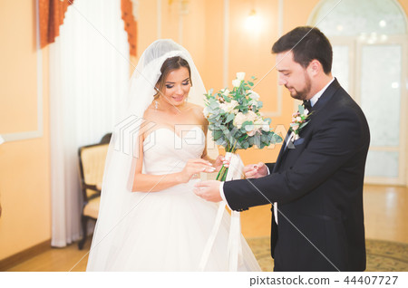 Beauty bride and handsome groom are wearing rings each other. Wedding couple on the marriage 44407727