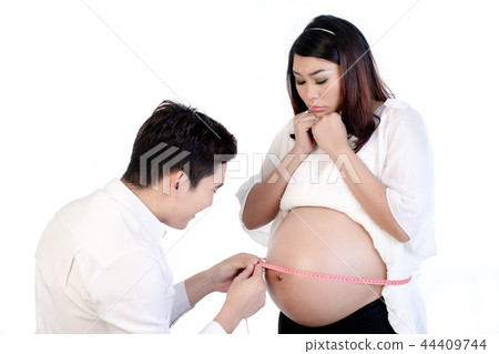 Husband measuring his pregnant wife's belly with tape Husband measuring his pregnant wife's belly with tape 44409744