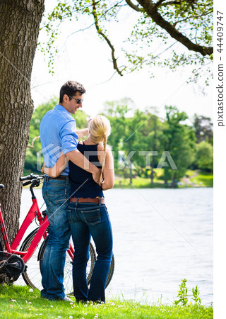 Couple standing near the lake with bicycle 44409747
