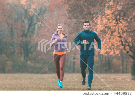 Couple in wonderful fall landscape running for better fitness Couple in wonderful fall landscape running for better fitness 44409852