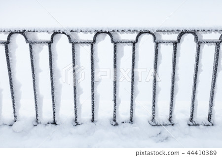 Forged black fence covered with snow, 44410389