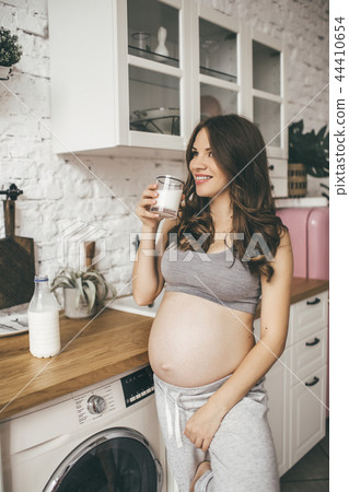 Pretty pregnant woman in kitchen having breakfast and cup of milk 44410654